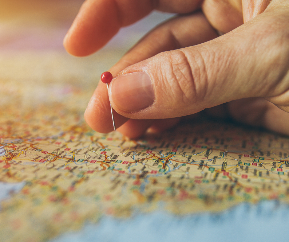 a hand placing a pin into a map